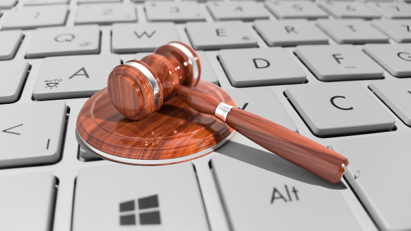 A wooden gavel lays on top of a white keyboard.