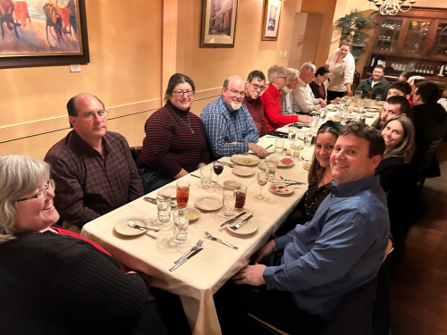 Picture of Keystone staff and their partners sitting at a long table in a private dining room during their 2023 Holiday Dinner held at Cafe Luna.