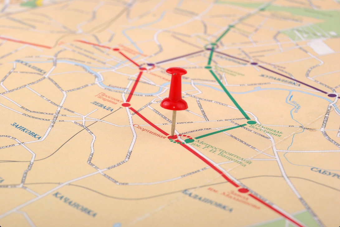 A roadmap with a red push pin placed at the point of two divergent routes.