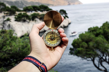 Point-of-view photo of someone holding a compass, looking ahead to a beautiful landscape.